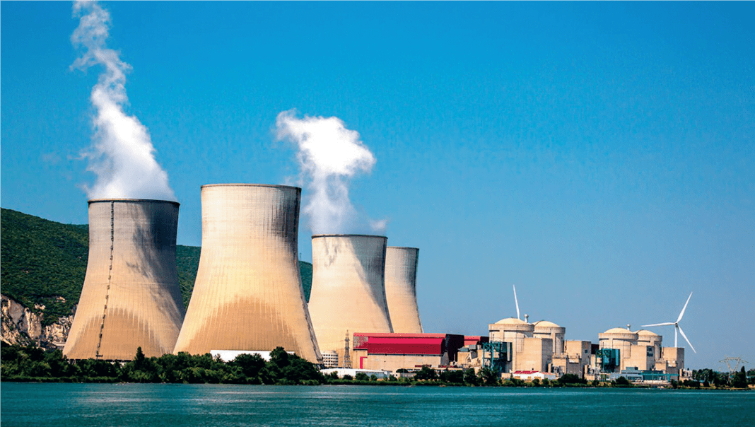 Le Maroc rayonne dans le nucléaire : Un avenir énergétique lumineux selon l’AIEA Centrale nucléaire avec tours de refroidissement et éoliennes au Maroc.