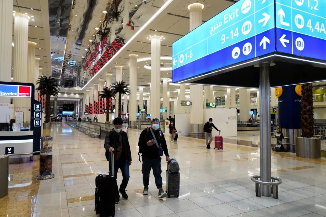 Aeroport de Dubai: il insulte le personnel et écope de 3 mois de prison Voyageurs avec valises à l'aéroport de Dubai, intérieur moderne et spacieux.