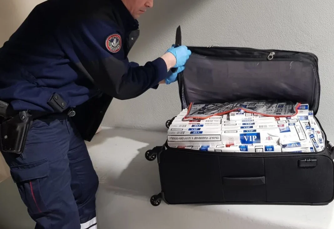 Aéroport de Lyon Saint-Exupéry: saisie de 5000 paquets de… Agent de sécurité manipulant des paquets dans une valise ouverte.
