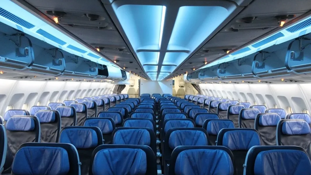 Alerte! Avion : En Hiver, n’occupez jamais ces sièges, sinon… Cabine d'avion vide avec sièges bleus et éclairage moderne.