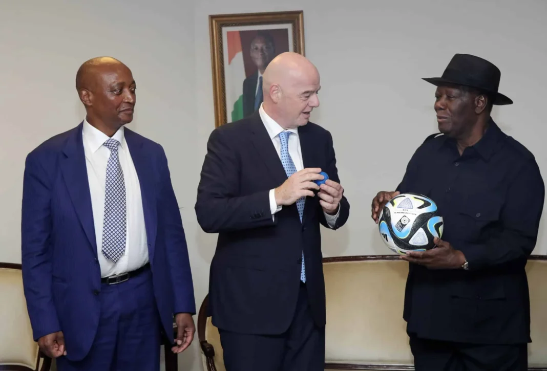Trois hommes en discussion, un tenant un ballon de football officiel de la CAN 2023.