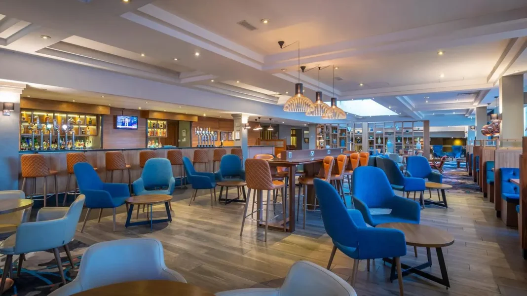 Important! Dans un restaurant d’hotel, évitez de faire cette grave erreur, au risque de… Salon de restaurant d'hôtel avec chaises bleues et ambiance chaleureuse.