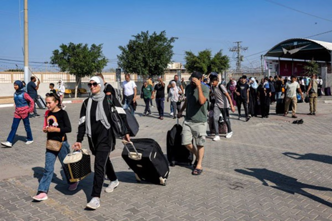 Gaza : 500 étrangers et binationaux évacués vers… Civils évacuant Gaza avec bagages dans un centre d'accueil.