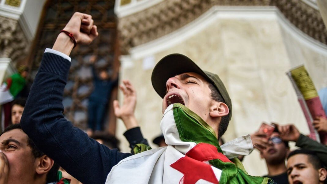Répression en Algérie : appel pressant d’Eurodéputés à des sanctions, la cinquième alerte en un An Jeune manifestant criant avec un drapeau algérien lors d'une protestation.