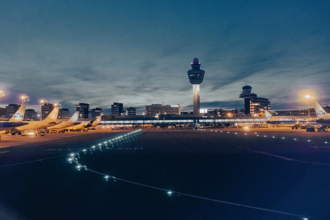 Transport aérien en France: Suppression de milliers de vols en 2024 Vue nocturne de l'aéroport avec avions et tour de contrôle.