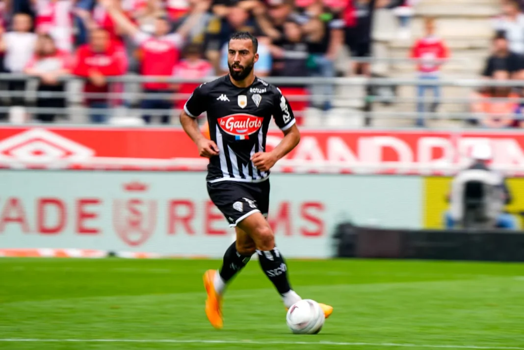 Abdelli réagit à son absence lors du précédent rassemblement en réponse à Belmadi ! Joueur de football en pleine action lors d'un match.