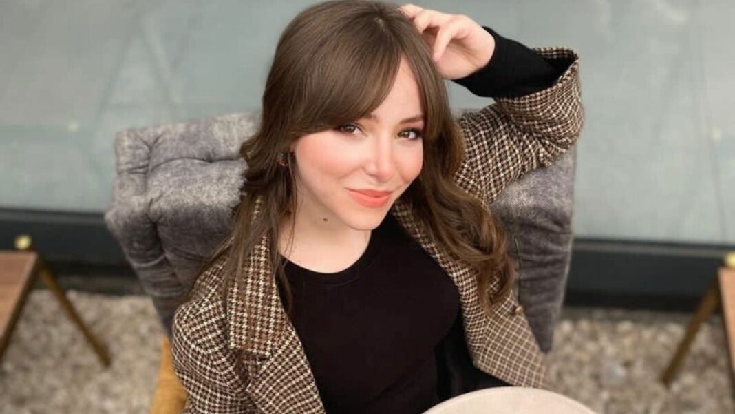 Jeune femme souriante en tenue élégante Jeune femme avec cheveux bruns et sourire charmant, assise dans un fauteuil.