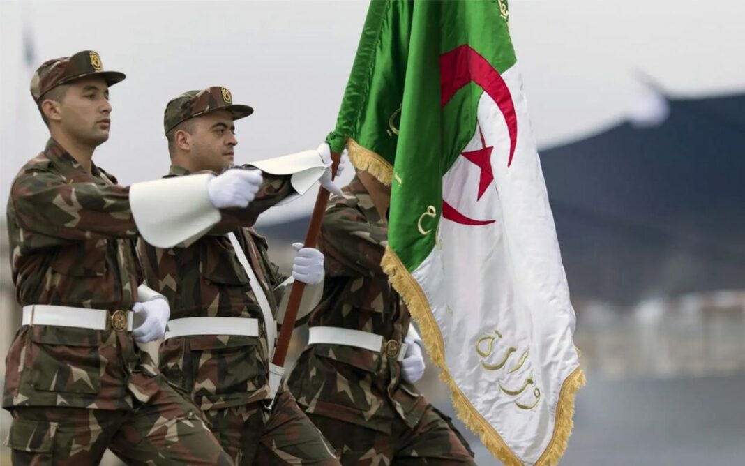 Soldats en uniforme avec drapeau algérien lors d'une cérémonie militaire.