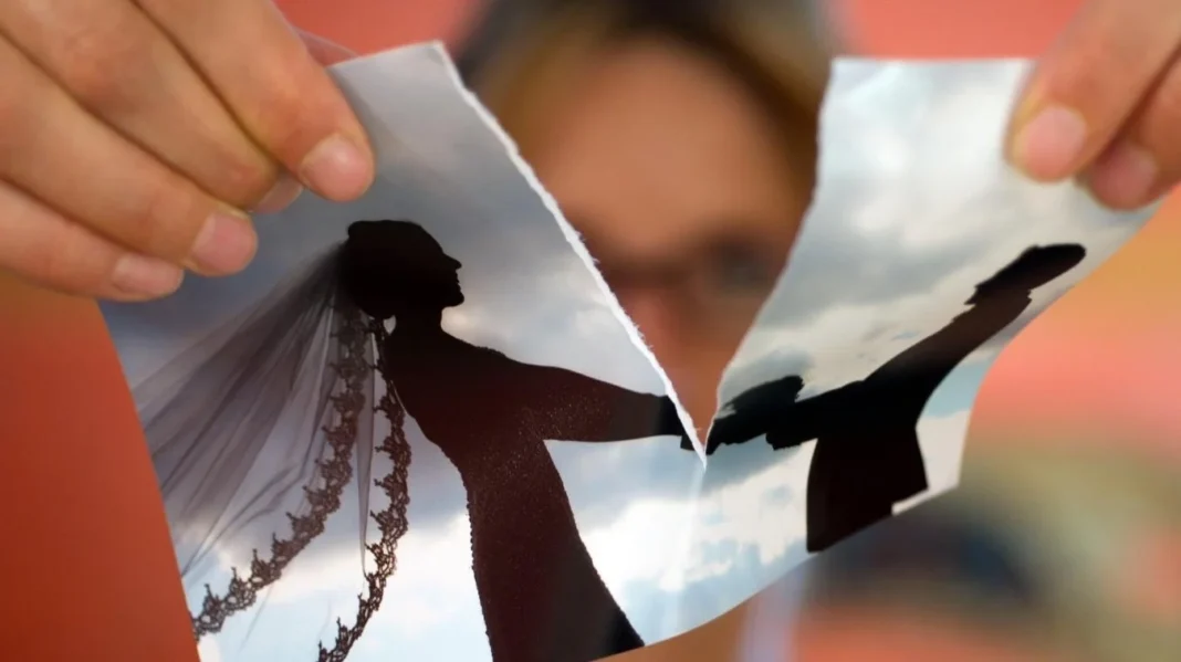 Tirage de photos de mariage Personne tenant une photo de mariage déchirée avec silhouette de couple.