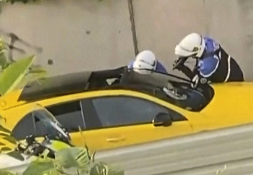 Policiers en intervention sur une voiture accidentée jaune.