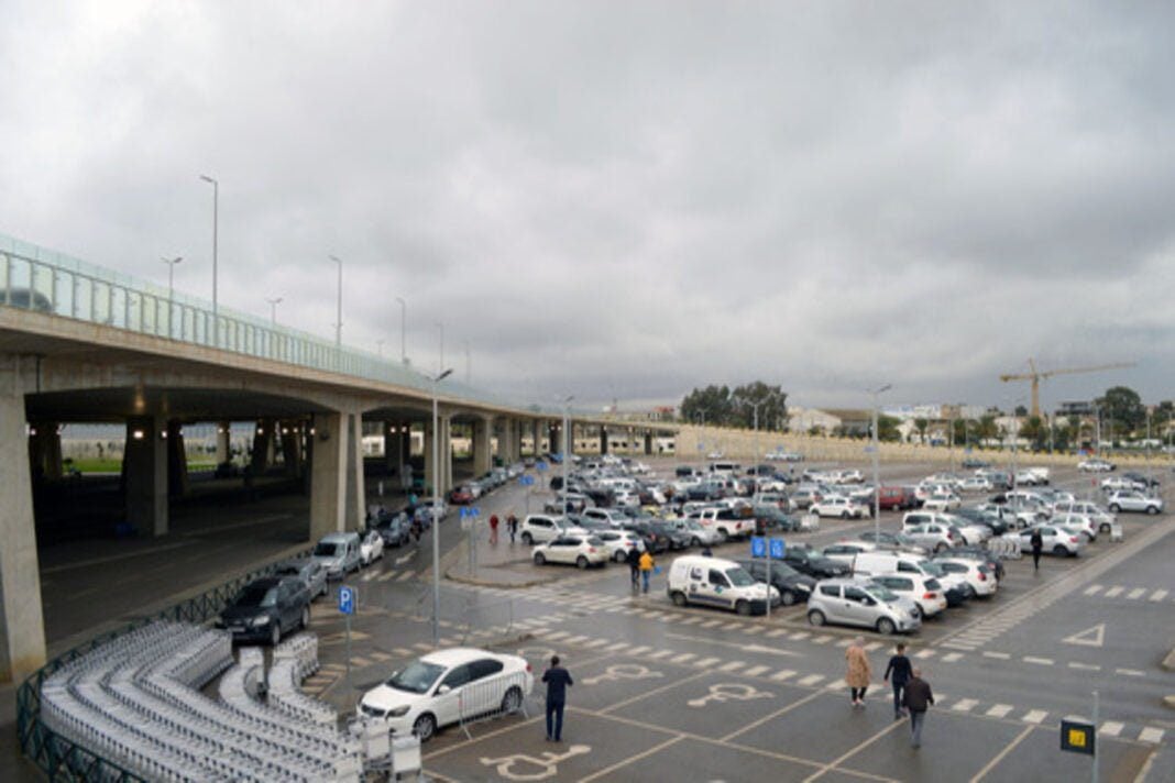 Aéroport d’Alger : Mise en garde concernant l’utilisation du dépose-minute au terminal Ouest Parking de l'aéroport d'Alger avec voitures et passagers sous un ciel nuageux.