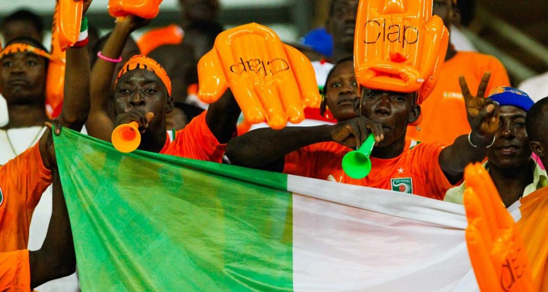 CAN 2023 : vers un record historique des ventes des tickets ? Supporters de la CAN 2023 avec drapeaux et accessoires orange.