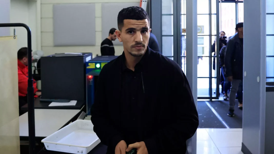 De retour en Algérie, voici ce que Youcef Atal déclare Youcef Atal dans un aéroport, regardant vers l'objectif.