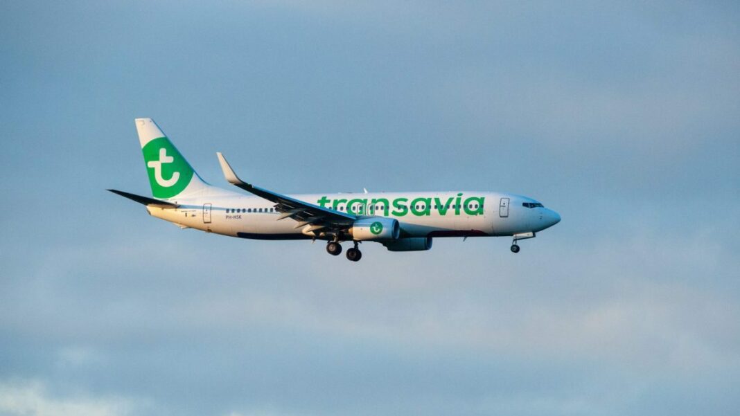 Avion Transavia avec logo vert en vol dans le ciel.