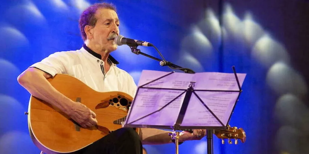 Chanteur algérien Aït Menguellet joue de la guitare en concert.