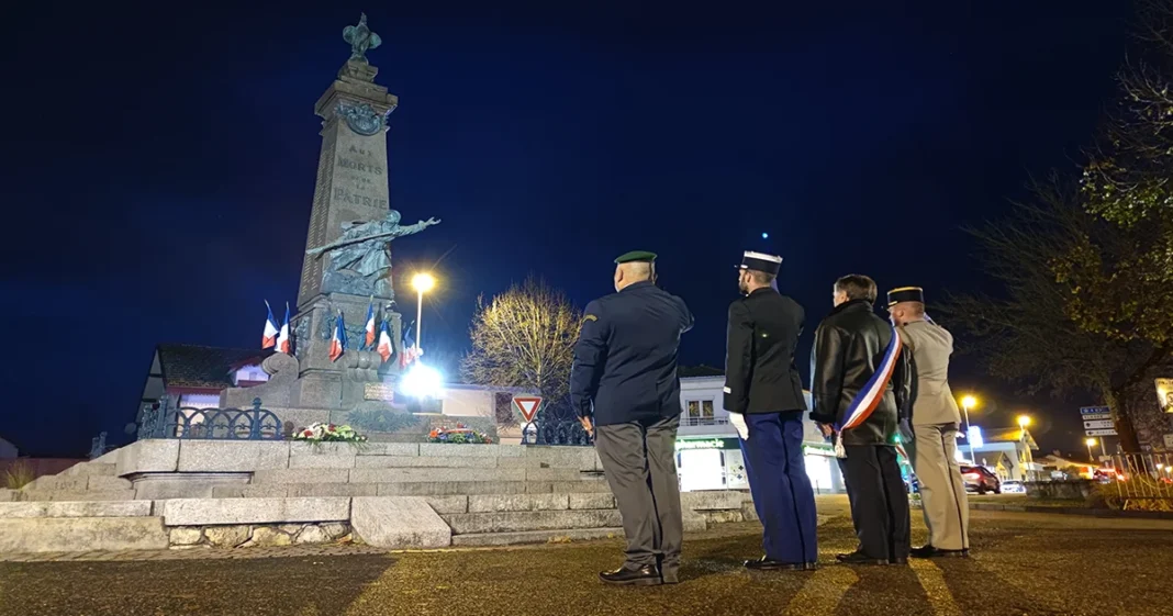 Hommage aux morts pour la France Cérémonie commémorative devant un monument aux morts en soirée.