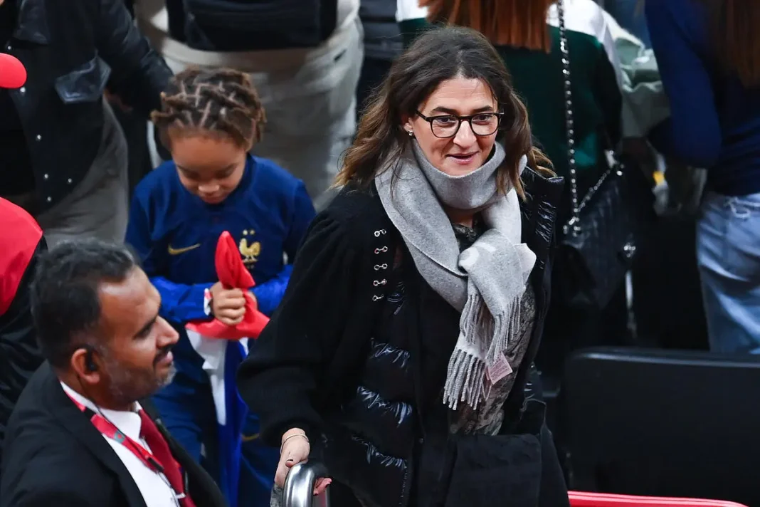 Coup de Tonnerre ! Fayza Lamari suspendue par la FIFA à cause de… Fayza Lamari portant un manteau noir et un foulard gris à l'aéroport.