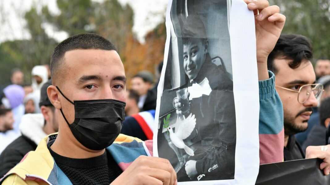 Jeune homme portant un masque lors d'une manifestation en mémoire d'Aymen.