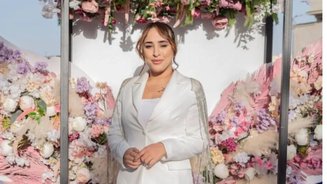 Maya Redjil posant devant un décor floral lors d'un événement à Alger.