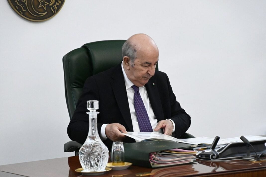 Président Tebboune en réunion, lisant des documents importants.
