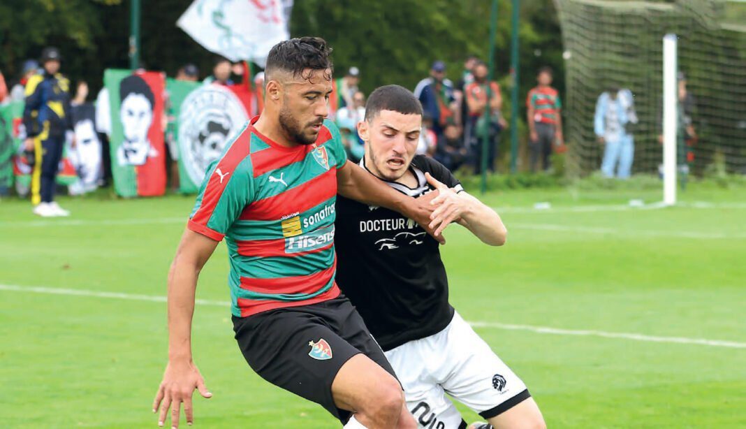 Youcef Belaili : Lumière brillante du Mouloudia d’Alger, applaudi par Belloumi Deux joueurs de football en action lors d'un match en plein air.