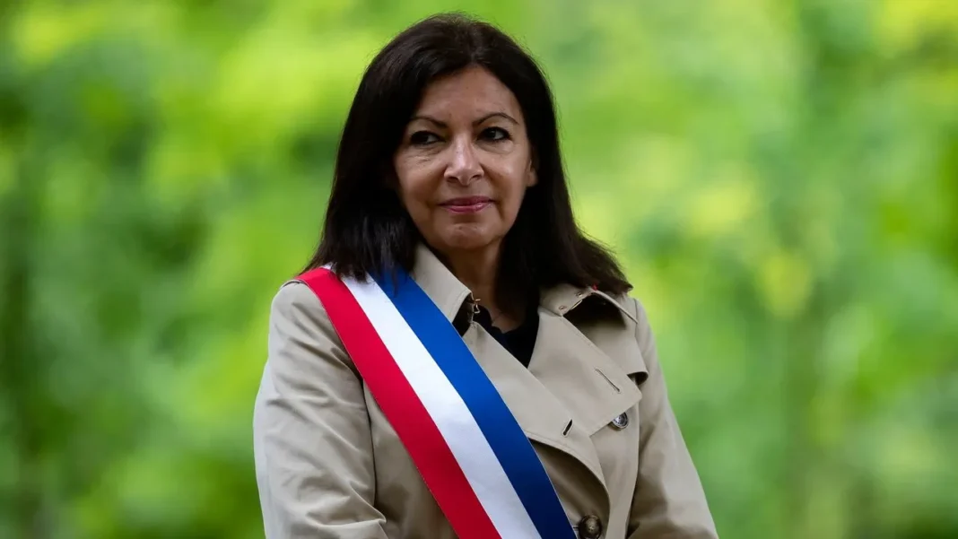 L’Humour Algérien déclenche un échange surprenant avec Anne Hidalgo Anne Hidalgo portant un sash tricolore lors d'un événement en plein air.