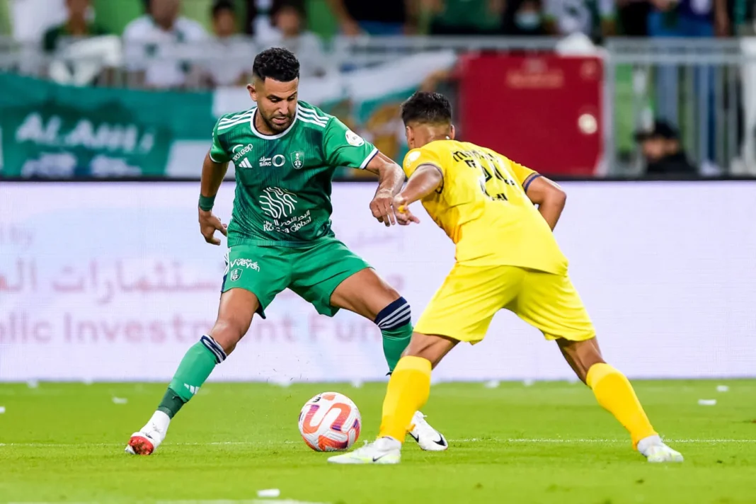 Riyad Mahrez en action lors d'un match Riyad Mahrez dribble un adversaire lors d'un match de football.