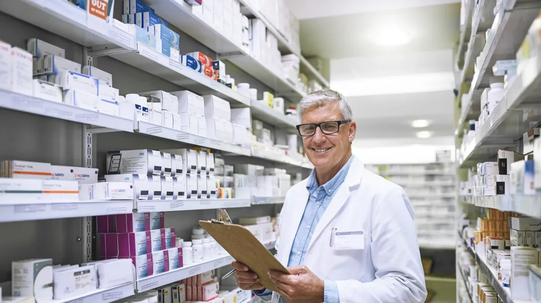 Pharmacien souriant tenant un clipboard dans une pharmacie algérienne.