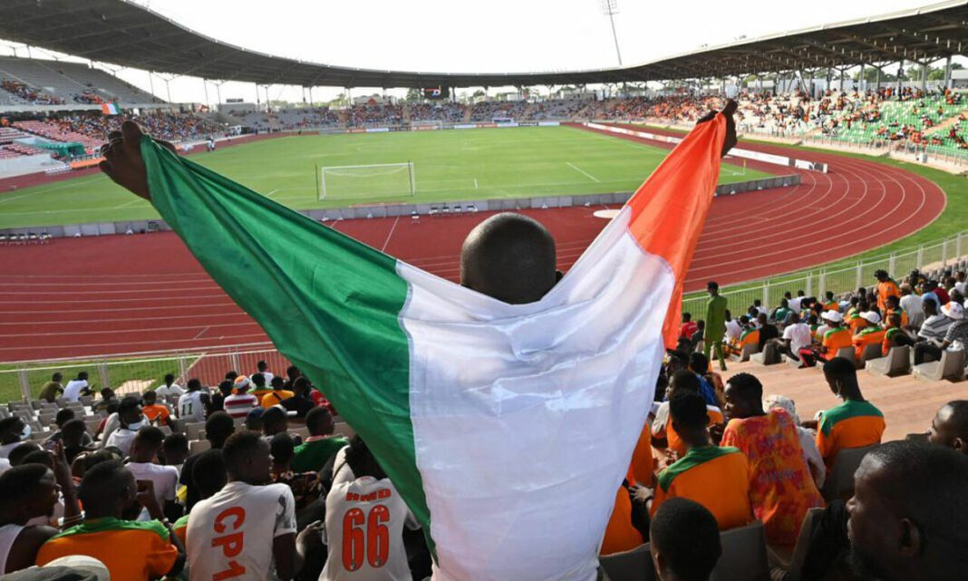 CAN 2023 : épopée footballistique imminente, anticipez l’inattendu ! Supporter avec drapeau national lors de la CAN 2023 au stade.