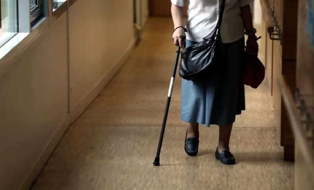 Femme âgée avec canne dans un couloir Femme âgée avec canne marchant dans un couloir d'hôpital ou de maison de retraite.