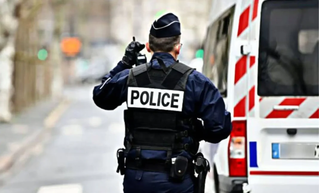 France/Établissement de faux papiers : 3 Algériens mis aux arrêts Policier en uniforme avec véhicule de police en arrière-plan.