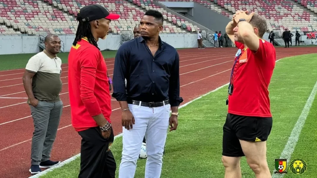 Trois hommes discutent sur le terrain de football en tenue sportive et décontractée.