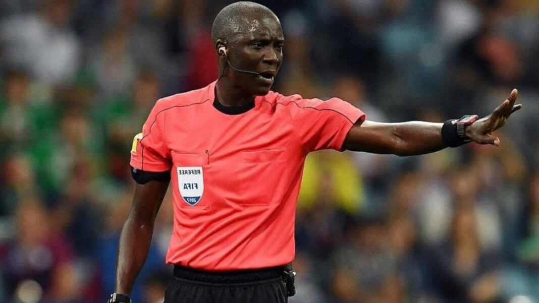 CAN 2024 : Retour du nom Gassama, une ombre du passé plane sur l’Algérie Arbitre en action lors d'un match de football, signalant une faute.