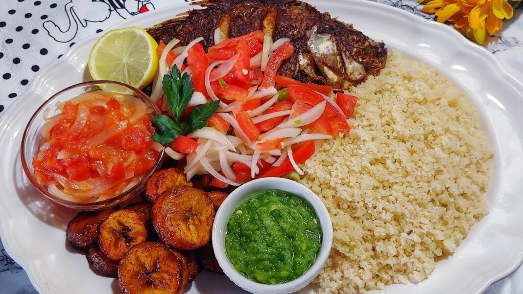 Plat ivoirien avec poisson, riz, bananes plantains et sauces colorées.