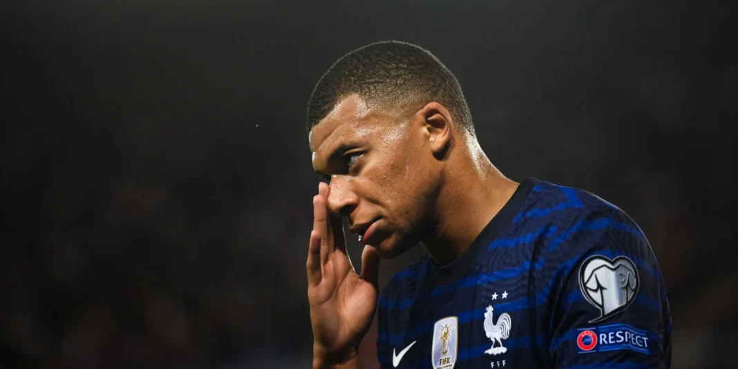 Blessure de Kylian Mbappe : la toile bombarde l’auteur d’insultes racistes Kylian Mbappé avec une expression préoccupée, portant le maillot de l'équipe de France.