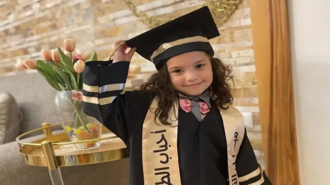 Jeune fille diplômée en graduation Jeune fille en robe de graduation souriante et tenant son chapeau de diplômée.