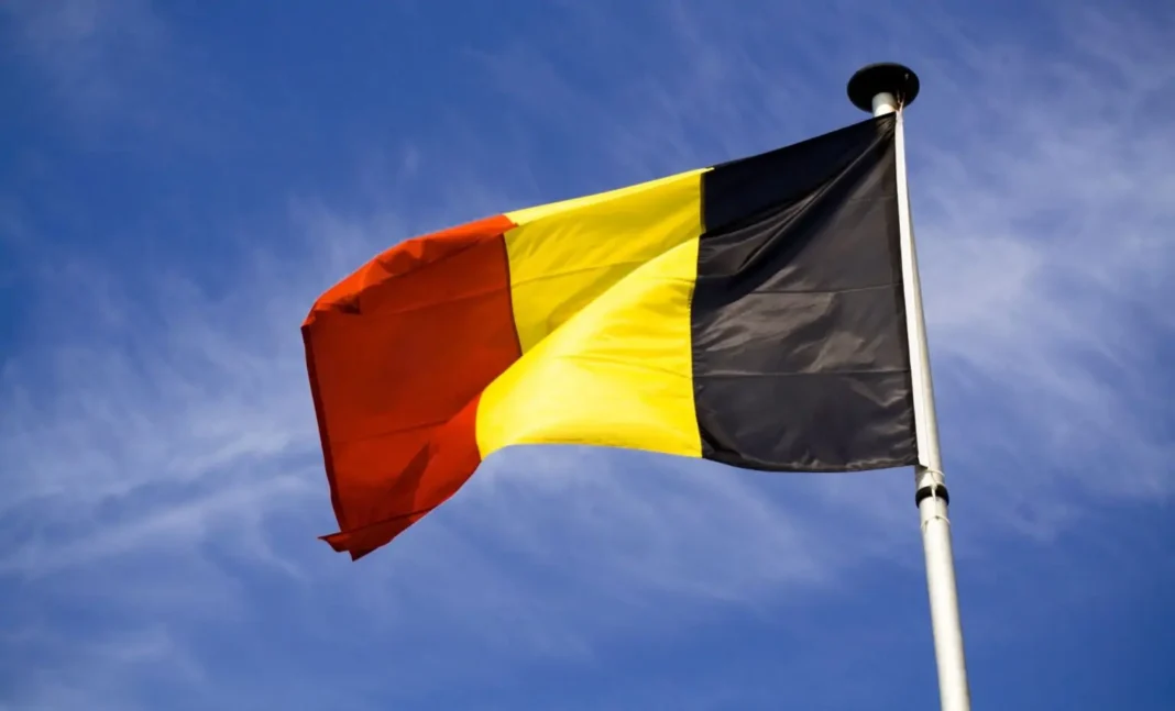 Immigration : Ultime porte de sortie pour la Belgique Drapeau national belge au vent contre un ciel bleu clair.