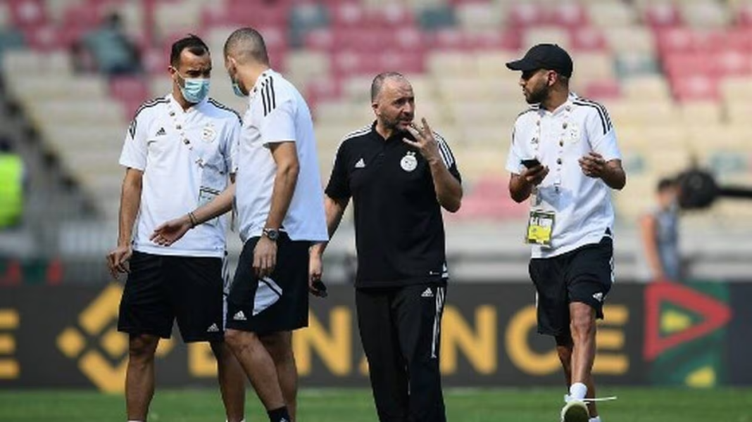 Équipe d'Algérie en discussion sur le terrain Les entraîneurs et joueurs algériens discutent lors d'un match.