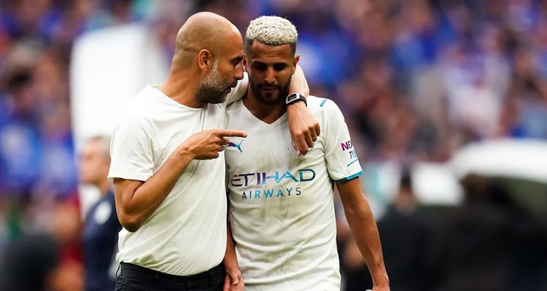 PL-Le ciel est bleu : Pep Guardiola réédite l’exploit, un an après le départ de Mahrez Pep Guardiola parle à Riyad Mahrez lors d'un match de football.