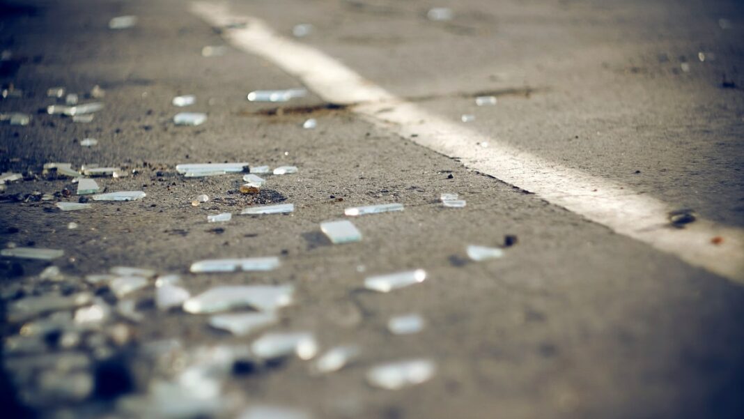 Débris de verre et débris sur la route suite à un accident de bus.