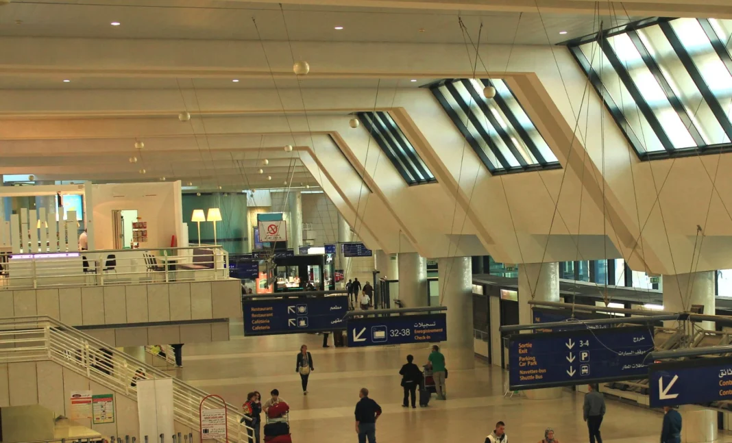 Aéroport d’Alger : Des Facilitations Exclusives pour ces voyageurs Vue intérieure de l'aéroport d'Alger avec zones d'attente et panneaux d'information.
