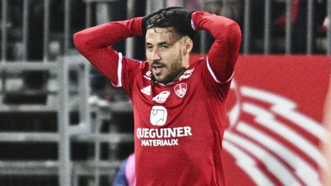 Belaili et les Clubs Algériens Sanctionnés : Les Dernières Nouvelles de la Ligue 1 Joueur de football en maillot rouge, expression de frustration.
