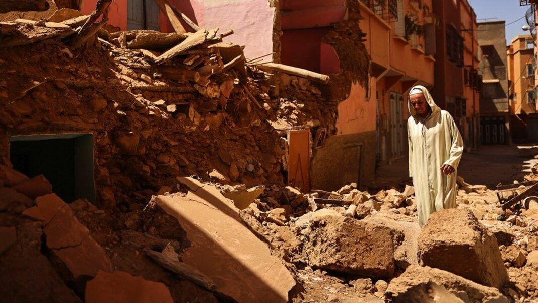 Séisme au Maroc : dégâts et sinistrés Homme en vêtements traditionnels devant débris de bâtiment effondré.