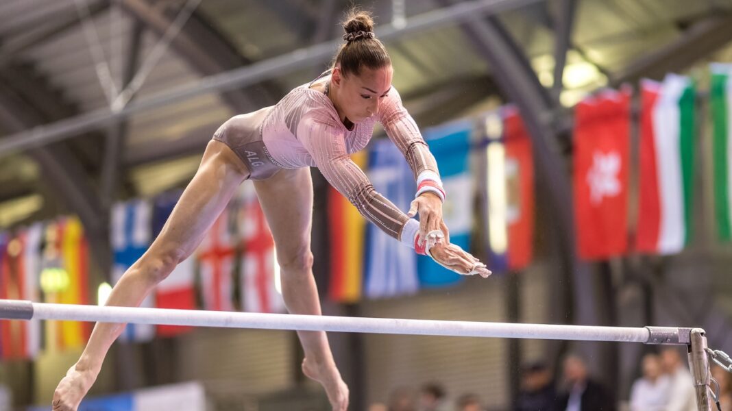 Kaylia Nemour : Deuxième Médaille d’Or à la Coupe du Monde de Gymnastique Gymnaste féminine effectuant une routine sur la poutre en compétition.