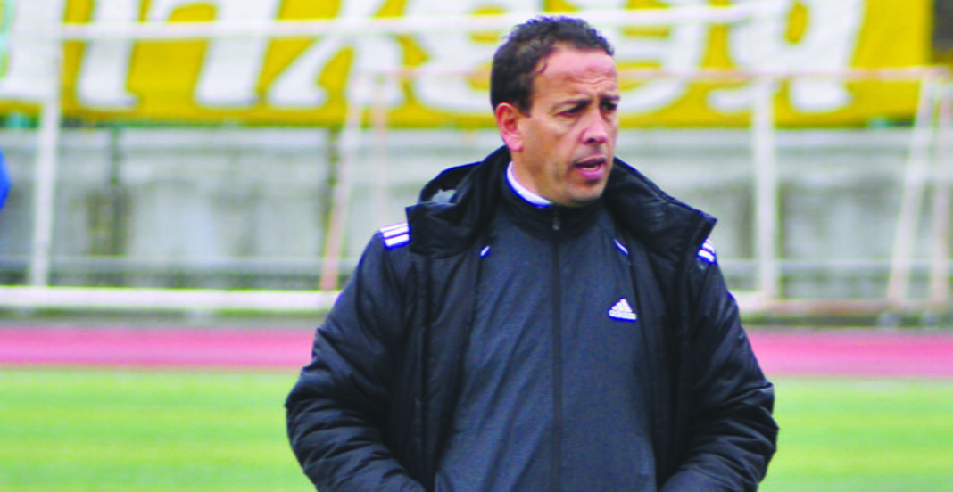 Entraîneur de football en pleine réflexion sur le terrain.