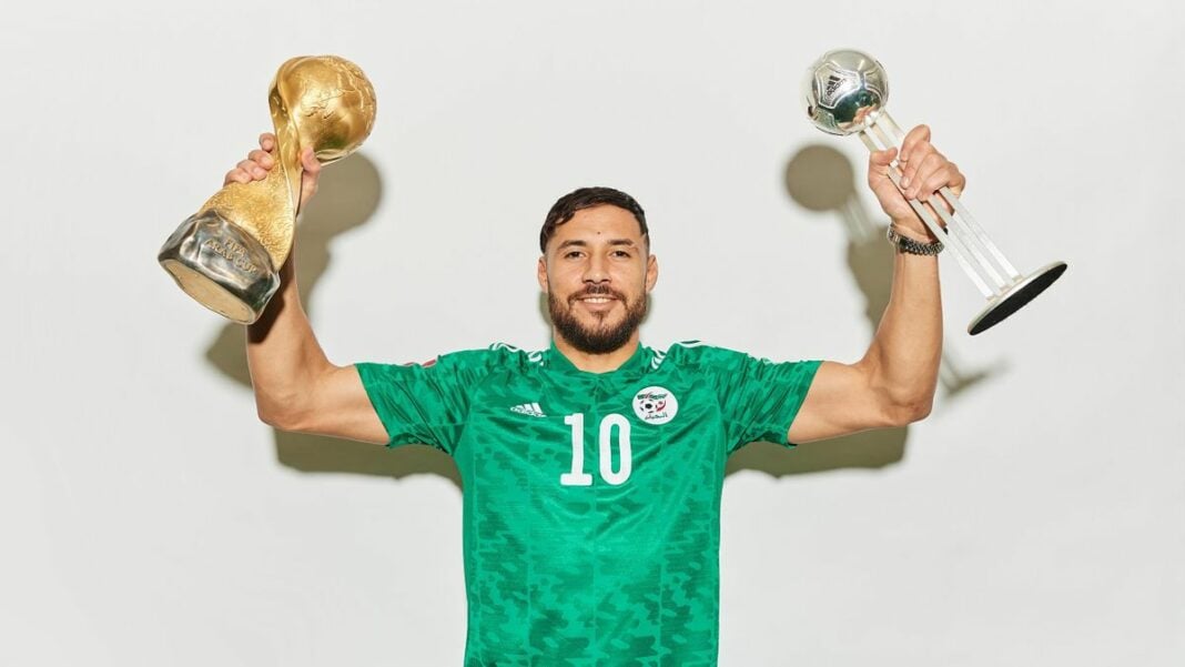 Belaïli célèbre sa victoire avec deux trophées de football.