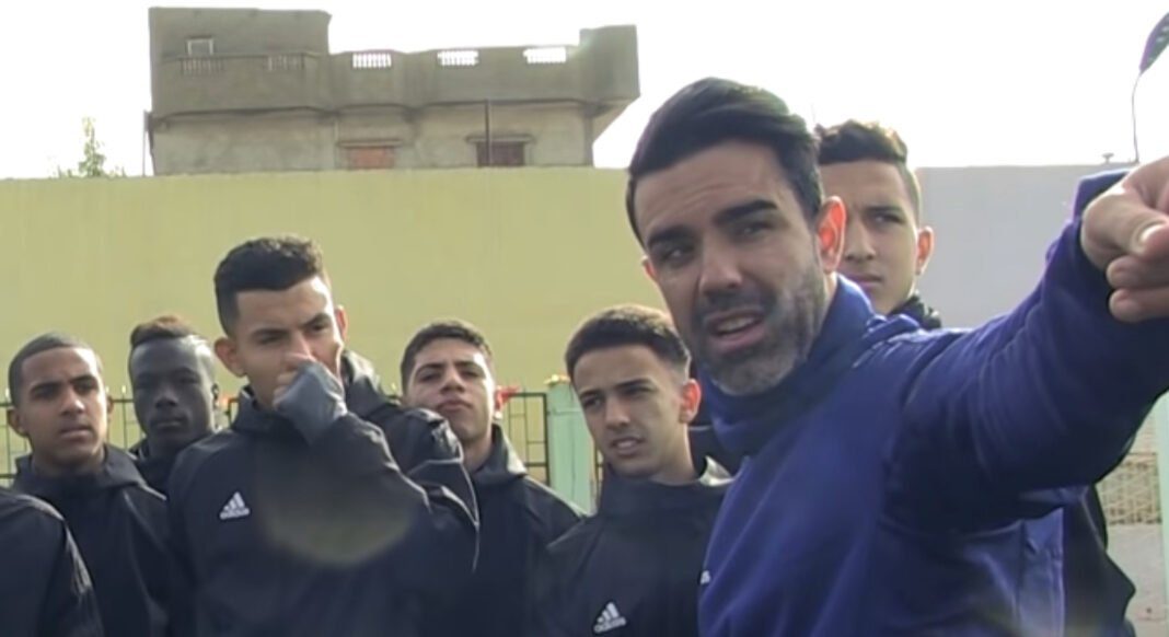 Vicente Girona lors d'une rencontre sportive Vicente Girona s'adressant à un groupe de jeunes sportifs en extérieur.