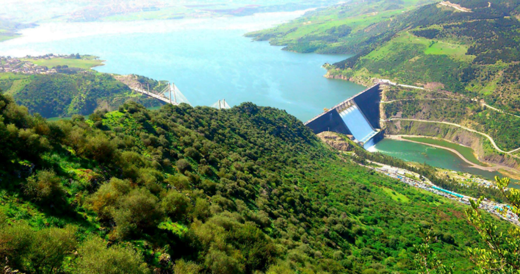 Béni Haroun : Le plus grand barrage d’Algérie rempli à 100% suite à des pluies bienfaisantes Le barrage de Béni Haroun, rempli après de fortes pluies, entouré de verdure et de montagnes.