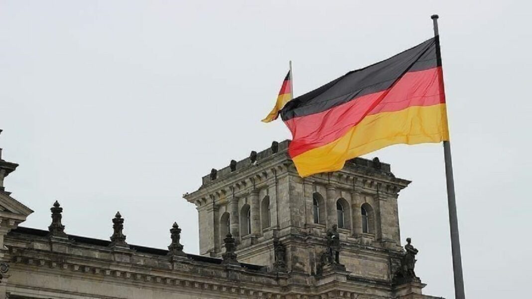 Drapeau allemand flottant devant un bâtiment historique en Allemagne.