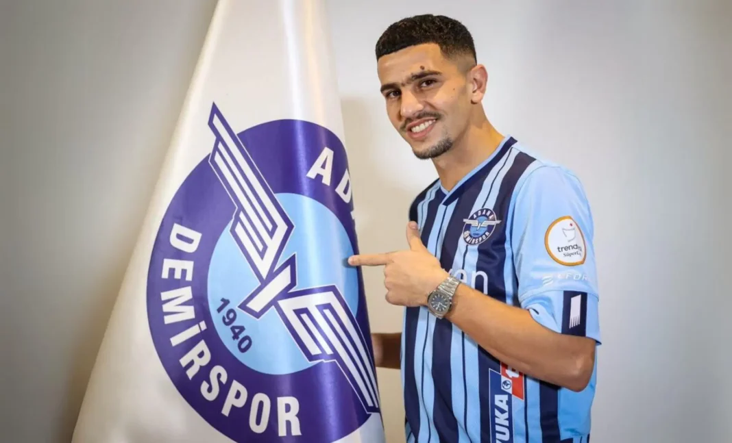 Mercato : Entre rumeurs et spéculations, quelle destination pour Youcef Atal ? Youcef Atal en maillot d'Adana Demirspor pointant le logo du club.